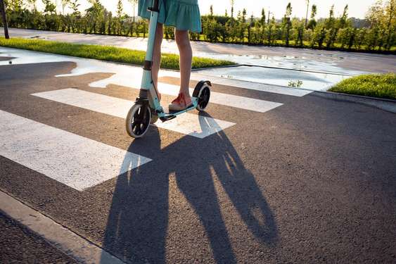 Kid mit einem Scooter auf einem Fußgängerüberweg