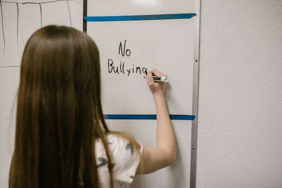 Kind schreibt "No Bullying" an das Whiteboard