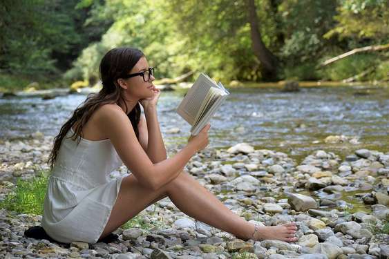 Frau liest am Fluss