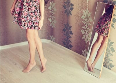 Frau betrachtet Beine im Spiegel