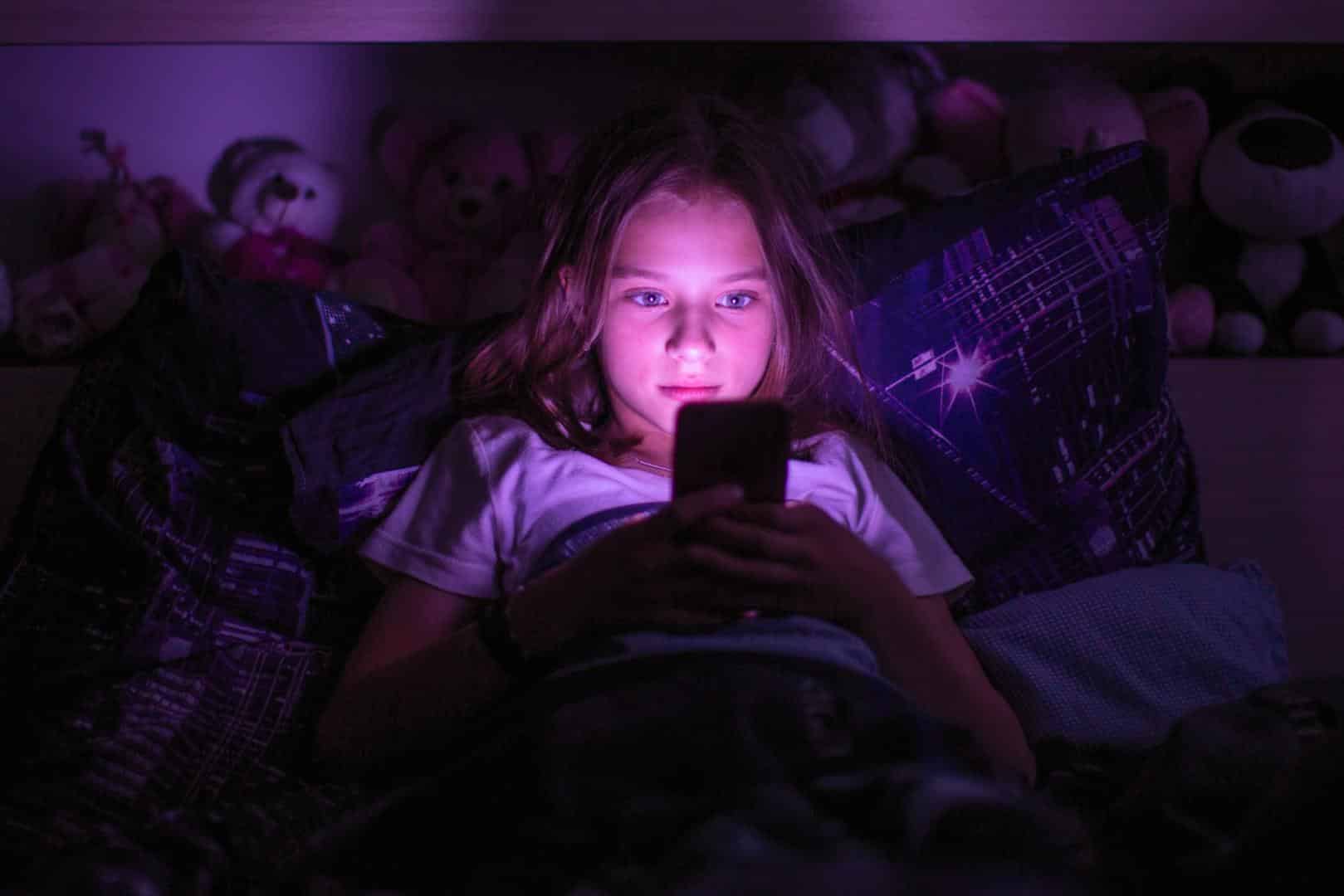 Kind nachts im Bett am Handy